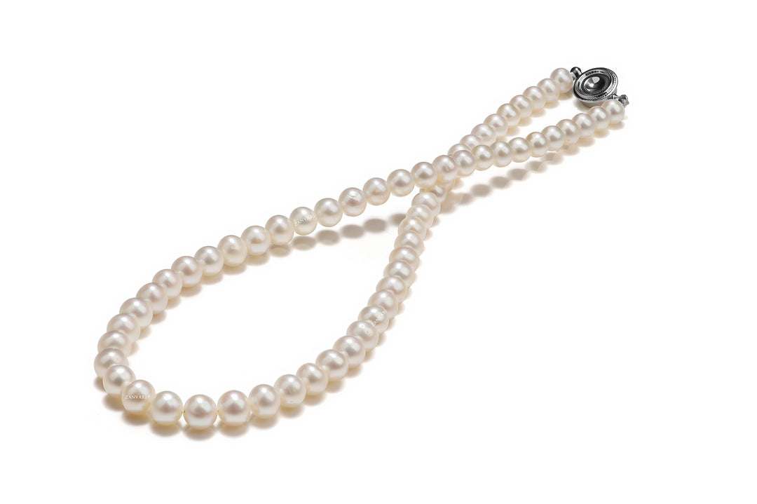 A pearl necklace on a white background. The pearls are white and round, and they are strung on a thin thread, a perfect gift for her.