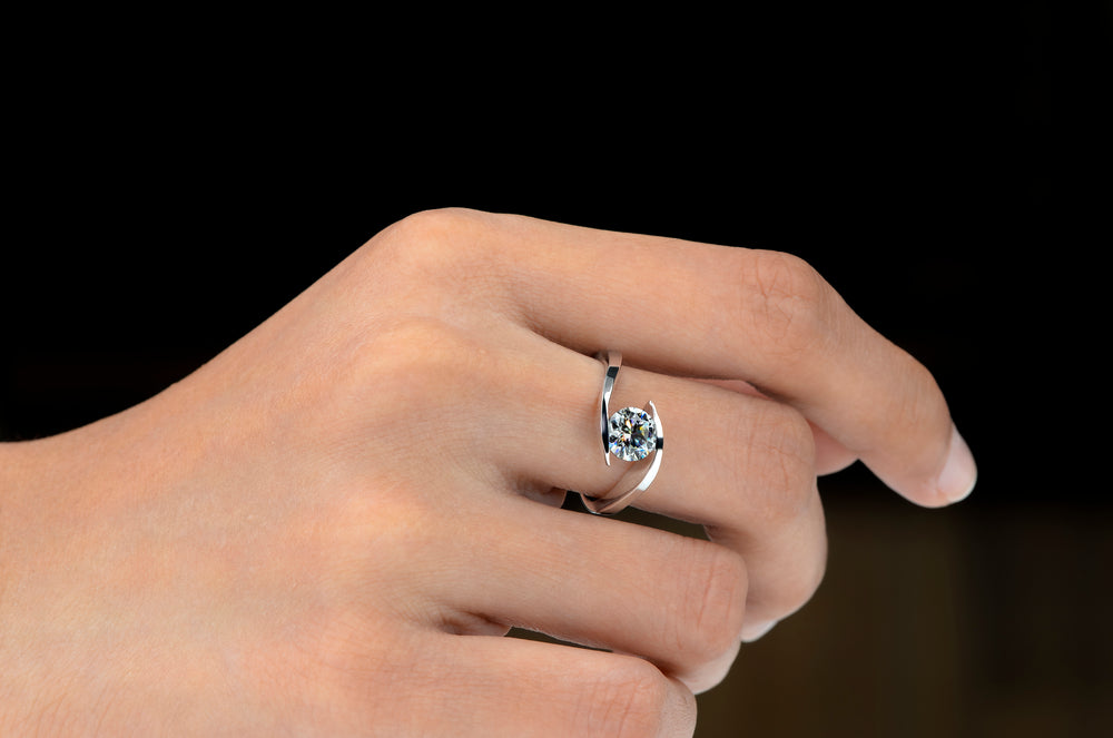 A woman's hand wearing a moissanite ring in sterling silver.