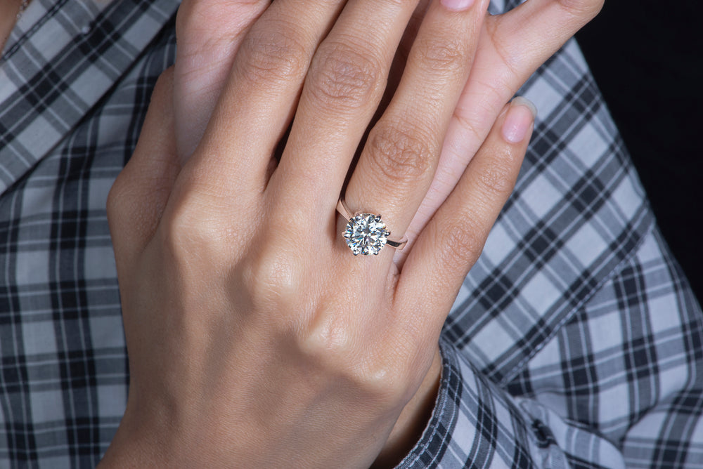 A hand wearing a 3-carat Moissanite ring, an alternative to diamond, set in a 925 sterling silver band.