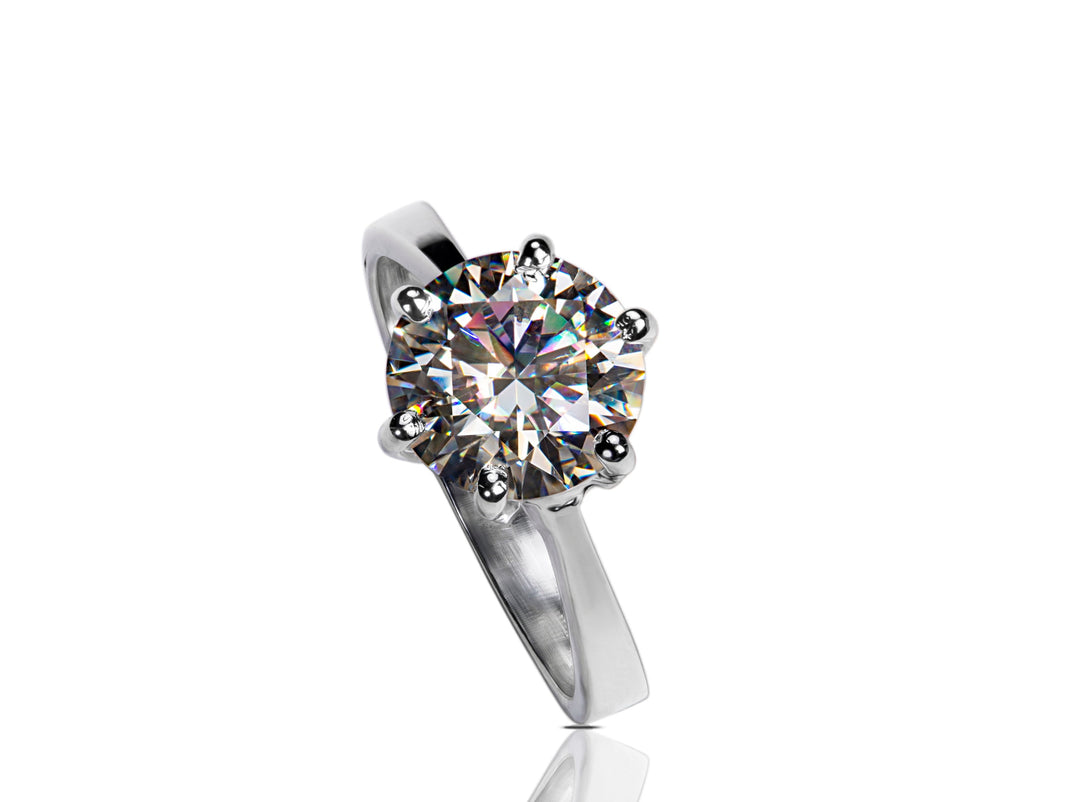  A 3-carat Moissanite, serving as an alternative to a diamond, elegantly set in a 925 sterling silver ring with a reflective white background.