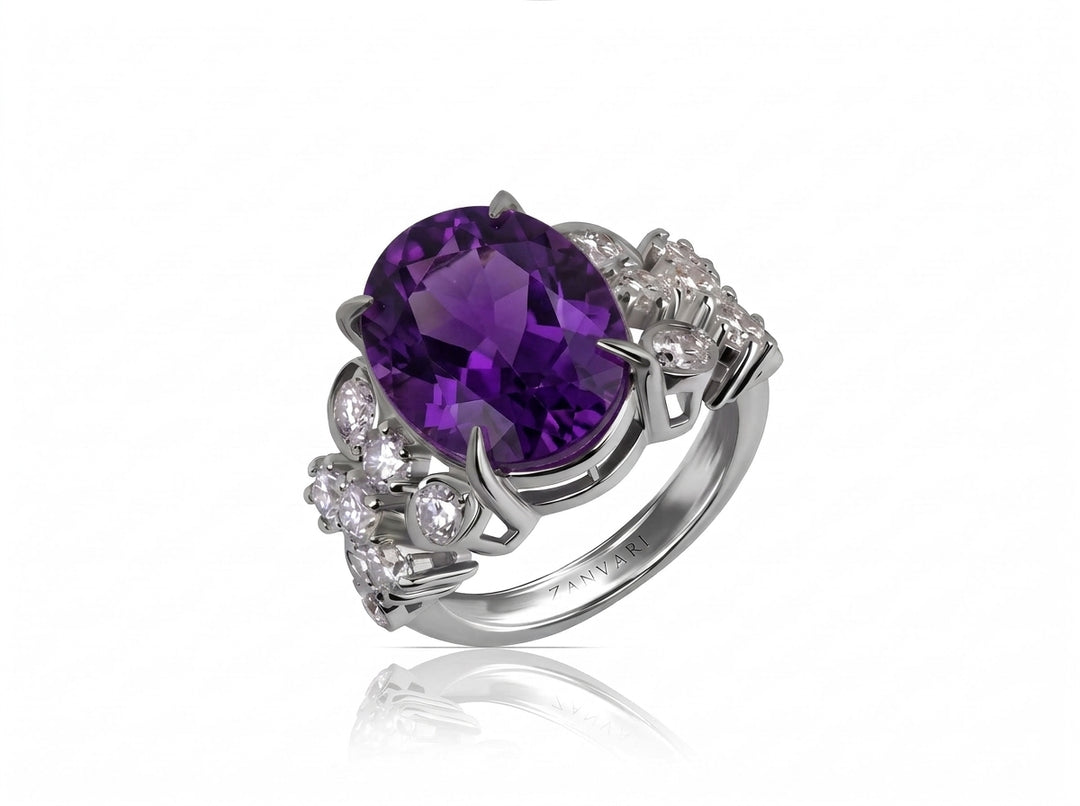 A silver-toned ring featuring a large oval-cut purple amethyst center stone, accented by small clear round diamonds along the shoulders, shown on a white background with a soft reflection.