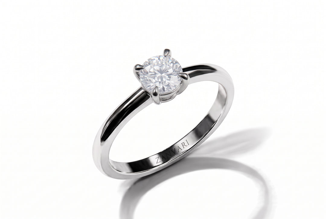 A silver solitaire engagement ring with a round brilliant-cut diamond set in a four-prong setting, shown on a clean white background with a soft shadow.