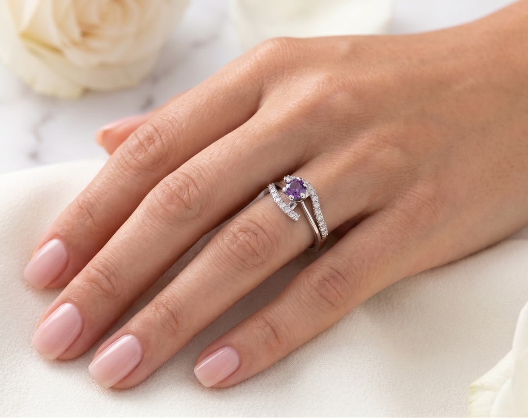 Hand wearing the Infinity Knot Amethyst Ring by Zanvari Pakistan — natural purple amethyst infinity knot ring in 925 sterling silver with flowers.