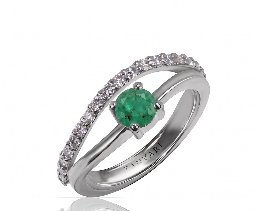 A silver ring featuring a round green emerald-cut center stone and a pavé band of clear cubic zirconia, displayed on a clean white background with a soft reflection below.