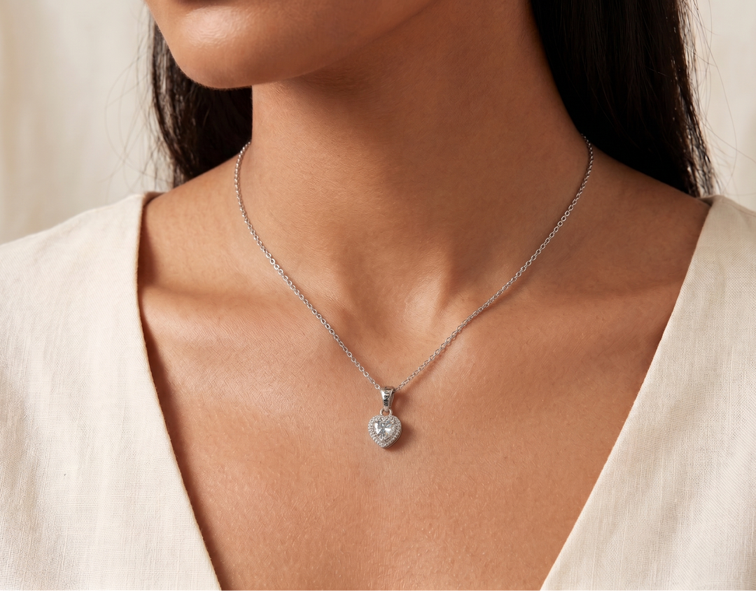 Necklace with a heart-shaped pendant worn by a person against a neutral background