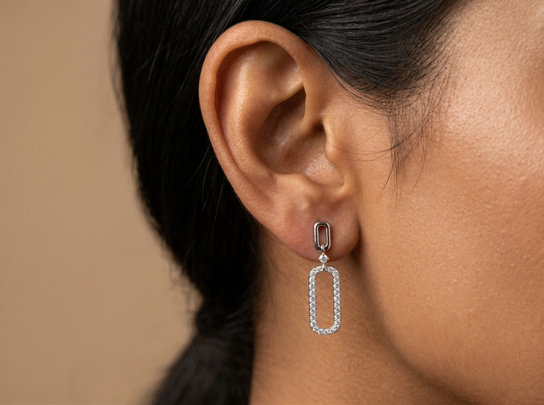 Close-up of a person wearing a silver earring with a beige background