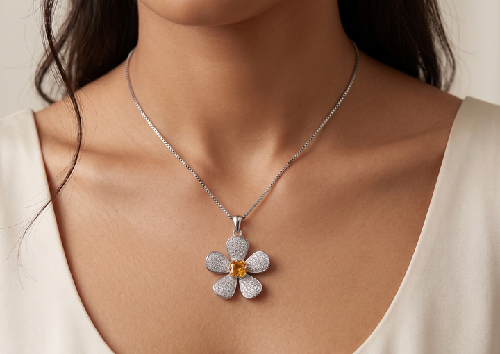 Woman wearing a silver necklace with a flower-shaped pendant featuring a yellow gemstone.