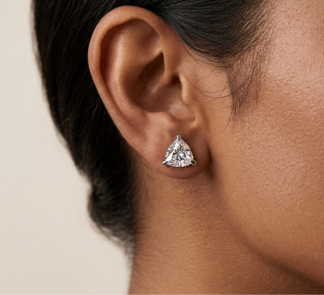 Close-up of a person wearing a moissanite earring on a neutral background