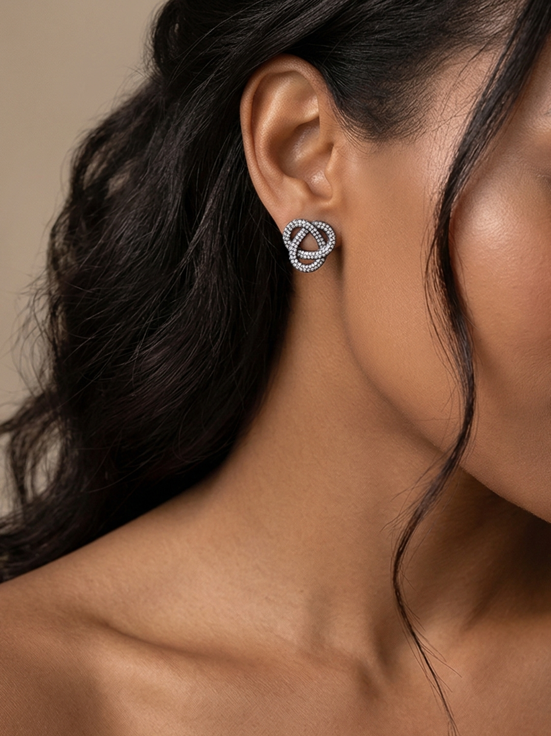 Woman wearing silver earrings with a neutral background