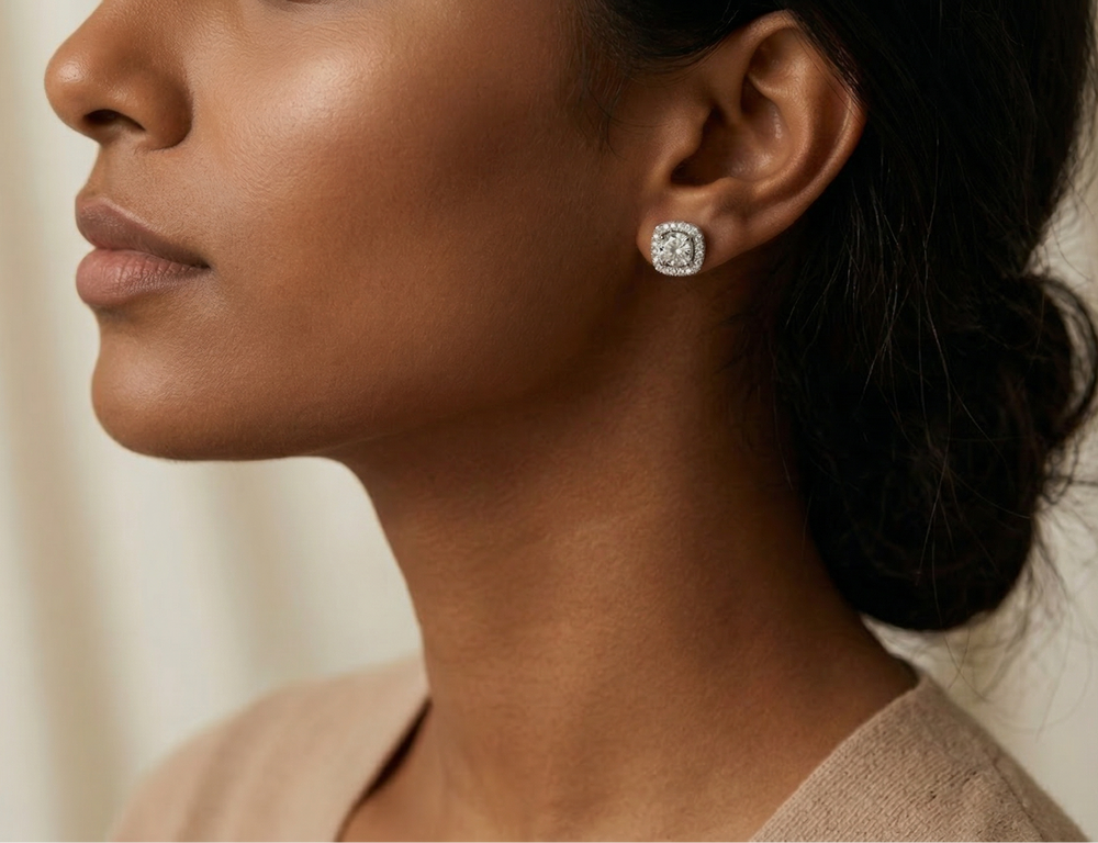 Close-up of a woman wearing moissanite studs with a neutral background