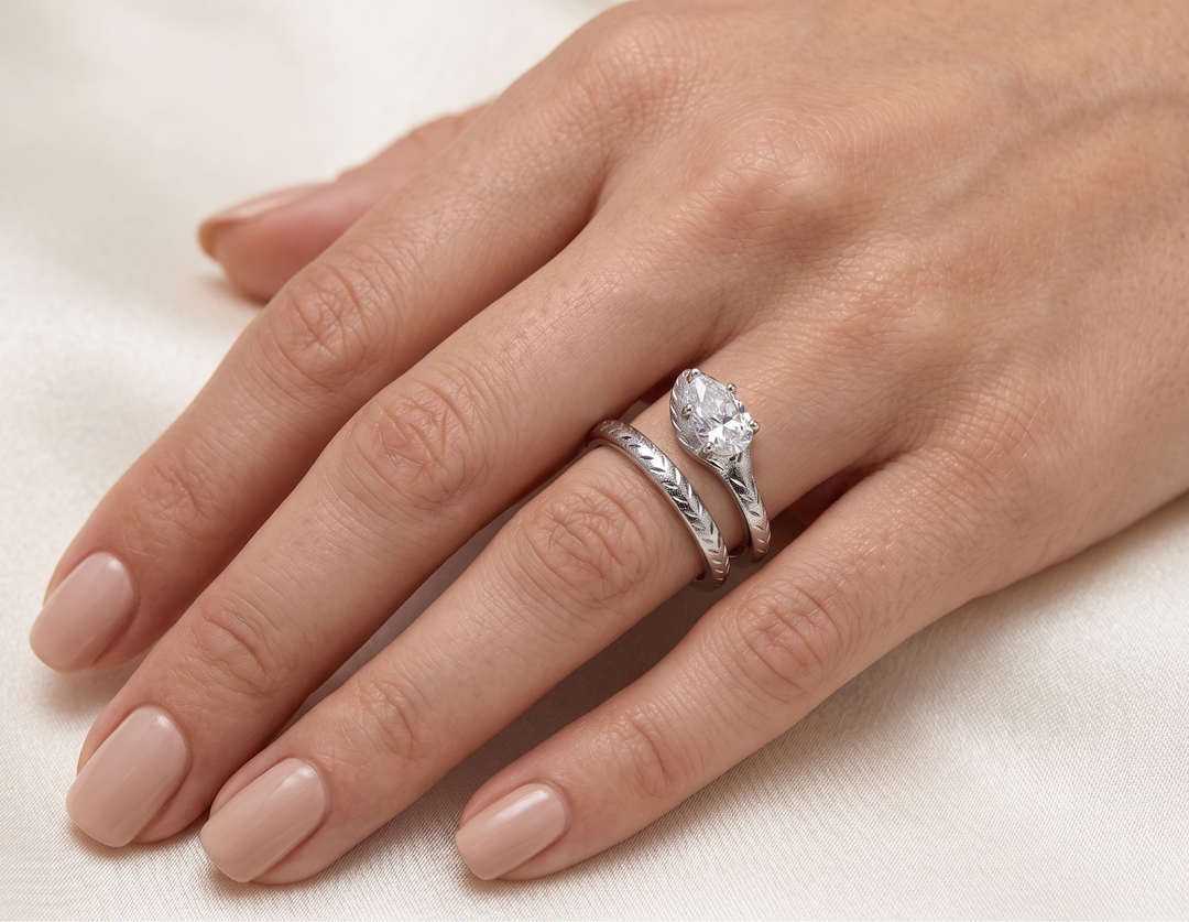 Hand wearing a pear shaped moissanite ring on a light background