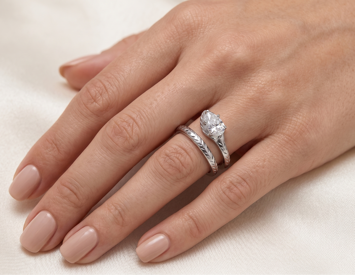 Hand wearing a pear shaped moissanite ring on a light background