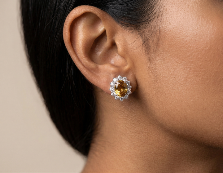 Close-up of an ear wearing a citrine silver earring with a beige background