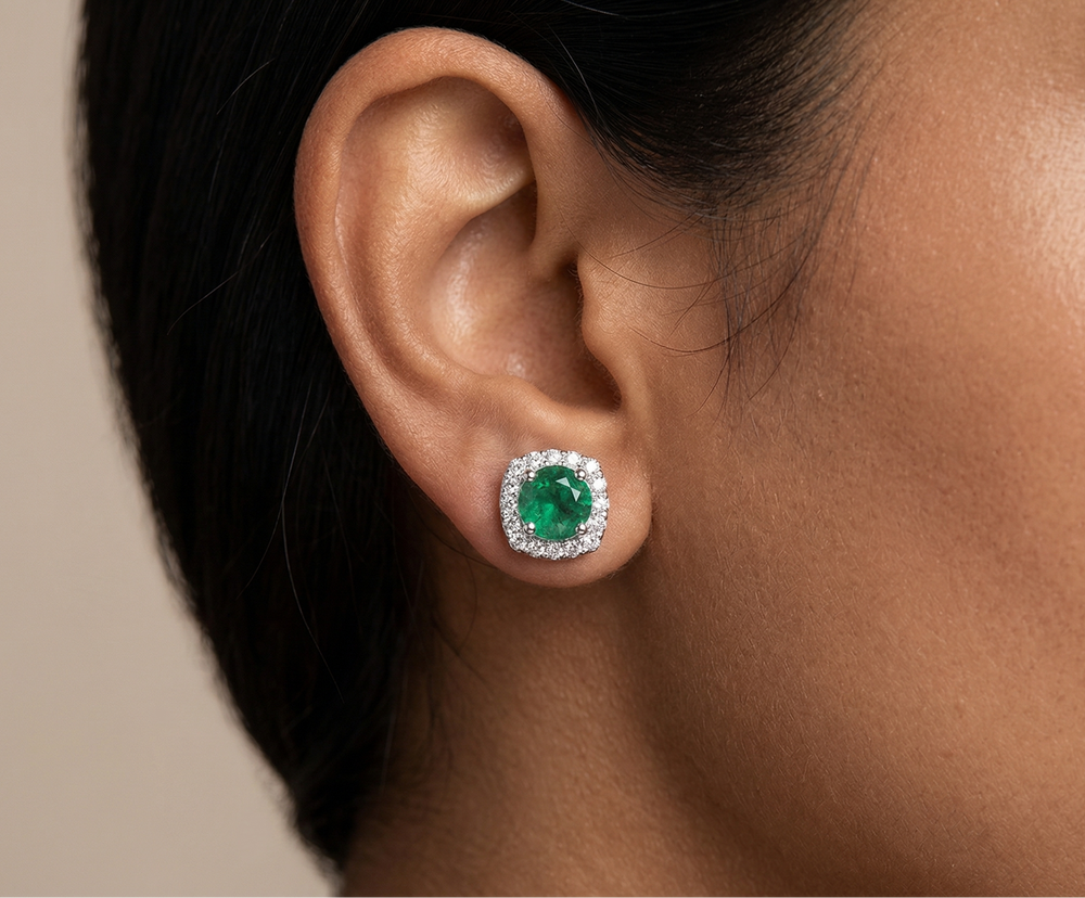 Close-up of an ear wearing a green gemstone earring against a neutral background