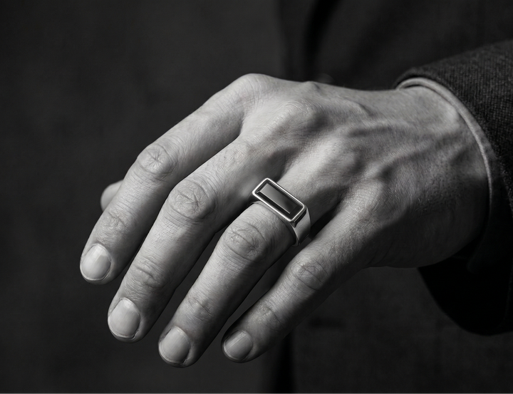 Close-up of a hand wearing a agate ring on a dark background
