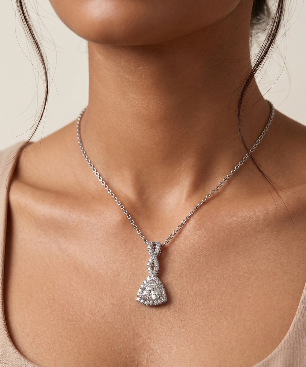 Silver necklace with a triangle moissanite silver pendant on a person wearing a beige top.