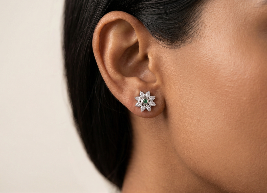 Close-up of an ear wearing a emerald  earring with a beige background