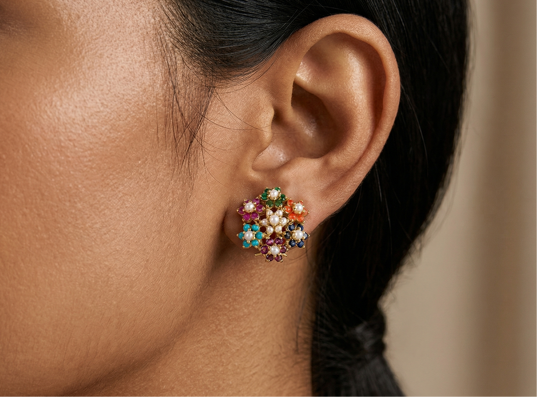 Close-up of an ear wearing a colorful gemstone earring with a blurred background
