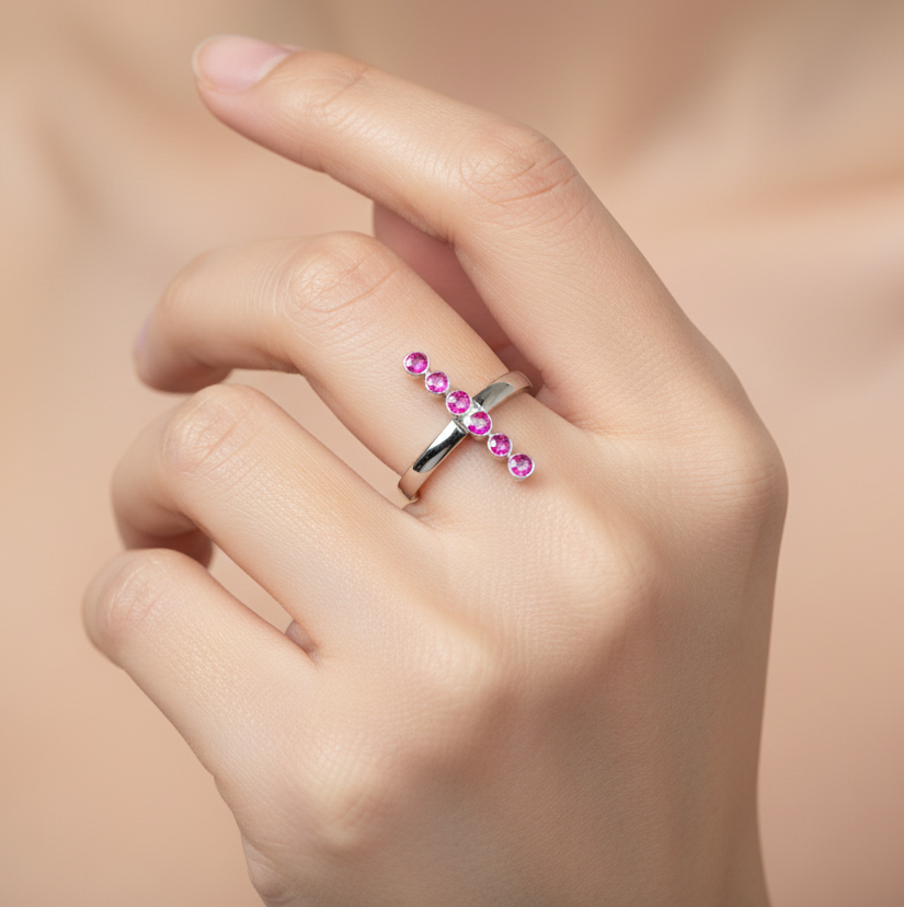 Silver ring with pink gemstones on a hand against a beige background