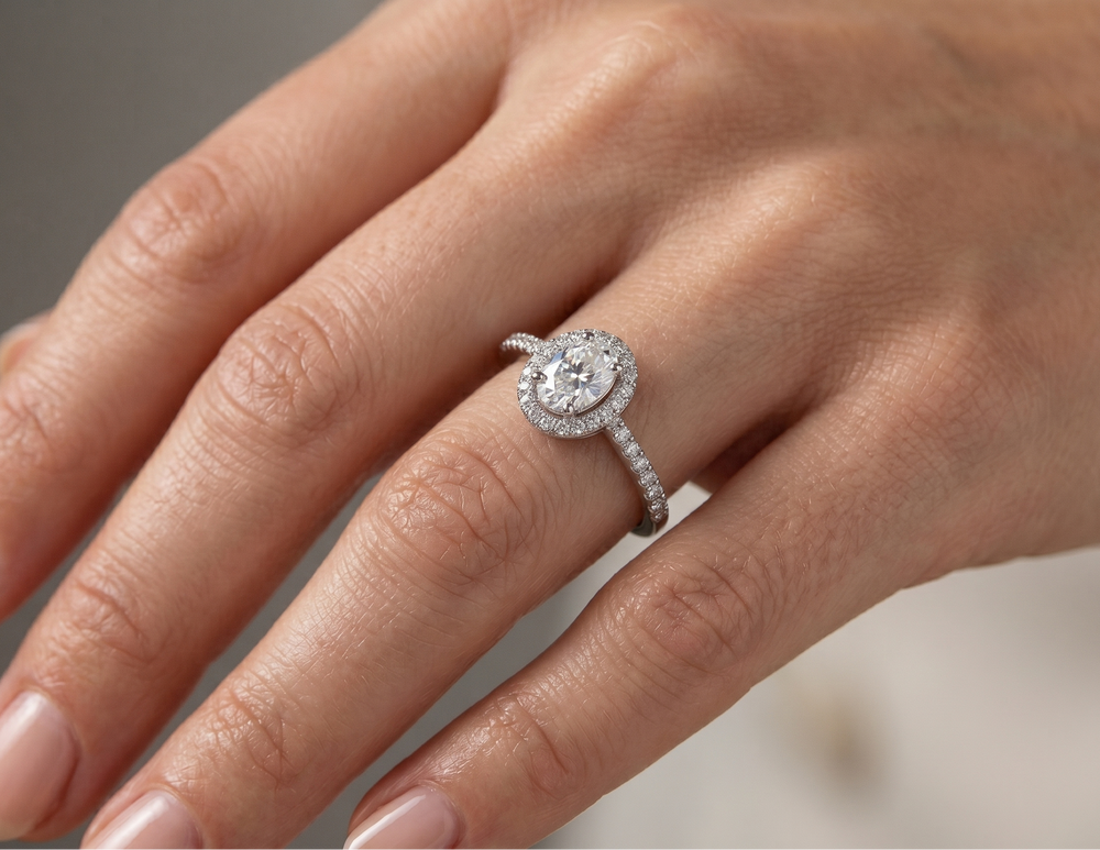 oval cut moissanite silver ring on a person's finger with a neutral background