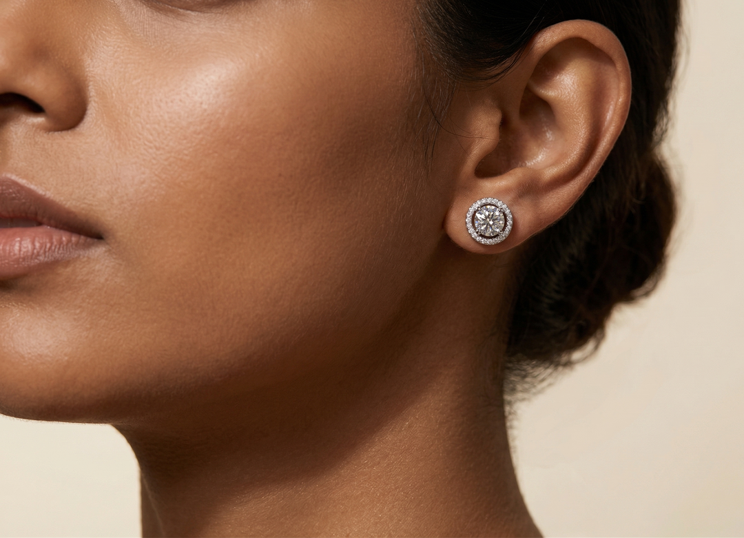 Close-up of a woman wearing a moissanite studs on a beige background