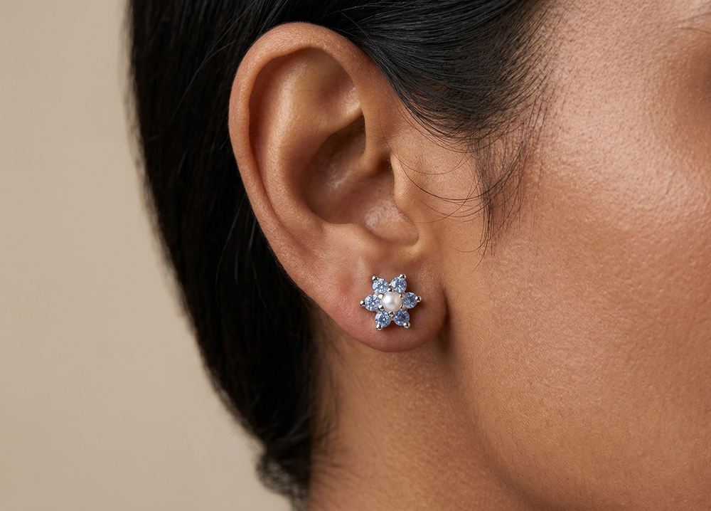 Close-up of an ear wearing a floral topaz earring with a beige background