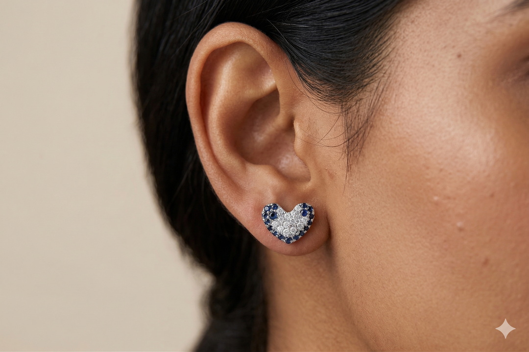 Heart-shaped earrings with blue gemstones worn by a person.