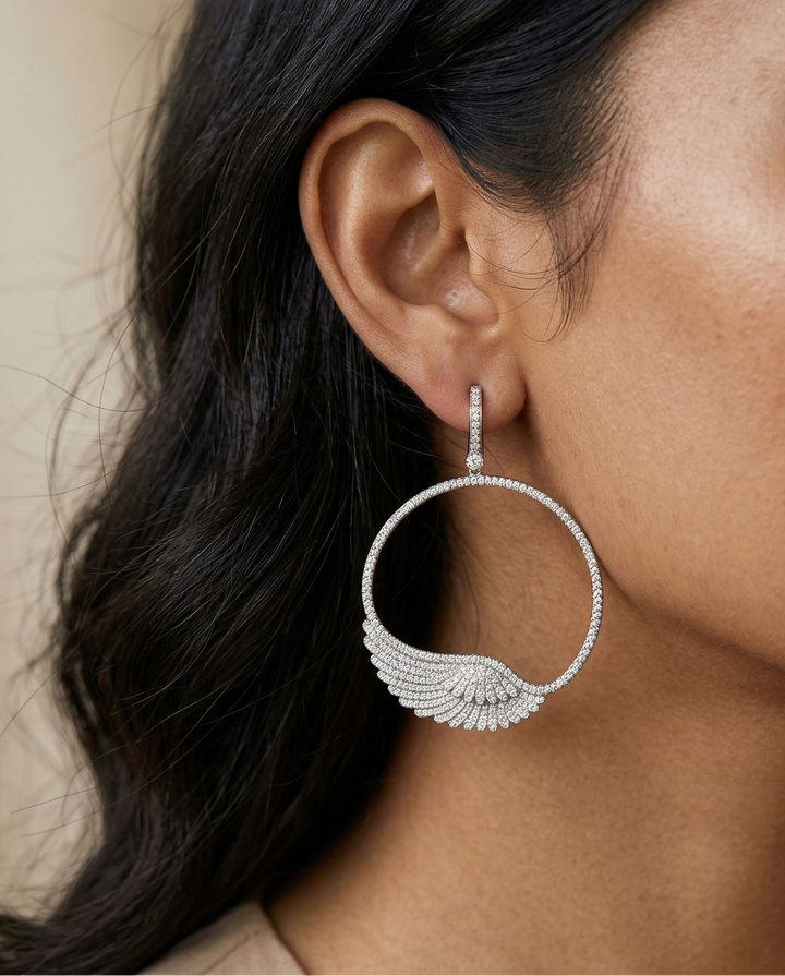Close-up of a woman wearing silver hoop earrings with a neutral background