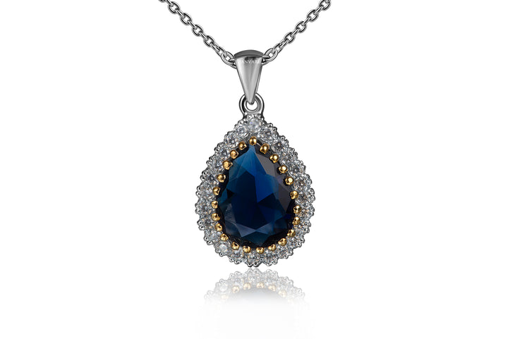 Teardrop-shaped pendant with blue gemstone and zirconia accents on a white background