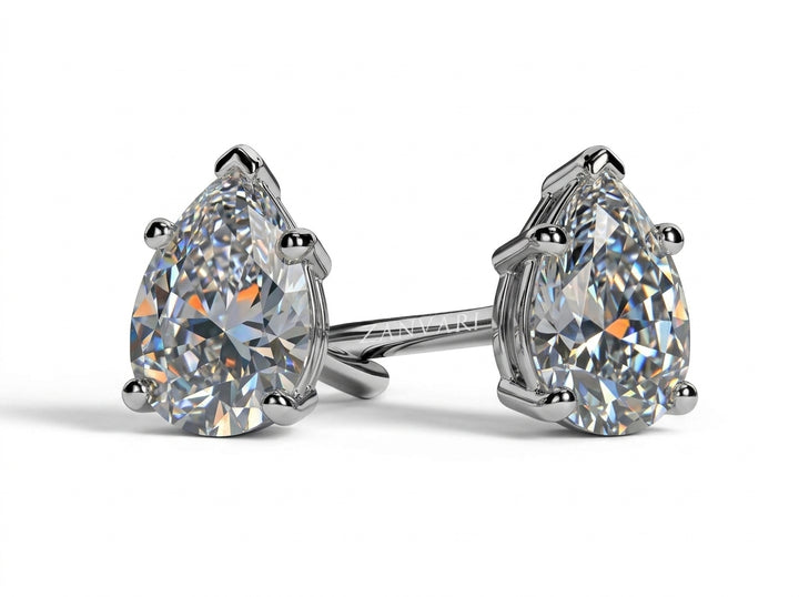 Studio shot of a pair of pear-cut solitaire diamond stud earrings in white gold prong settings against a white background.