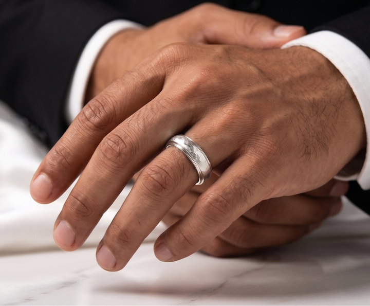 Close-up of a hand wearing a silver hammered  ring on a white fabric background