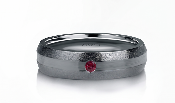A textured silver-toned band ring with a smooth horizontal center channel and a single round red  Ruby gemstone accent, featuring the brand name 'ZANVARI' engraved inside, on a clean white background.