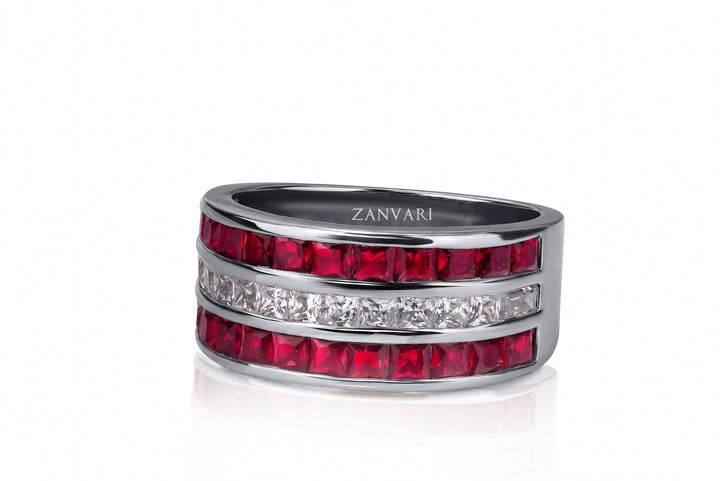 A silver band ring by Zanvari, featuring three horizontal rows of rectangular stones: two vibrant red stones and one clear diamond channel. The brand name 'ZANVARI' is engraved on the inside of the band.