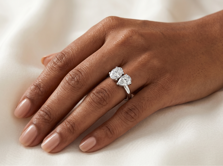 Hand wearing a Moissanite ring on a light background
