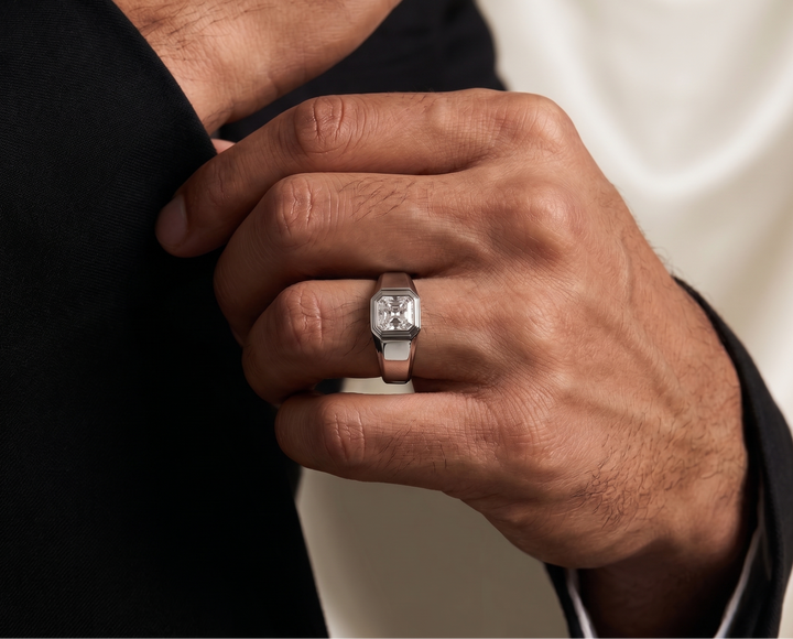 Hand wearing a moissanite wedding ring with a neutral background