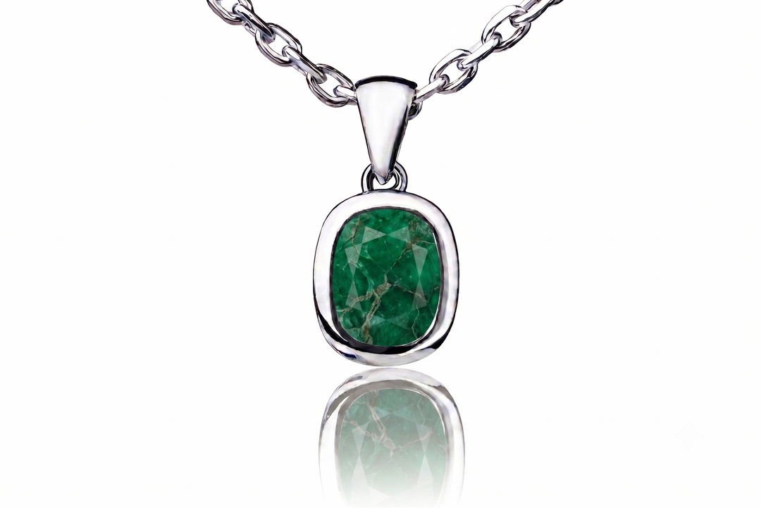 A silver pendant necklace featuring a cushion-cut green emerald gemstone with natural inclusions, suspended from a silver link chain against a white background with a soft reflection below.