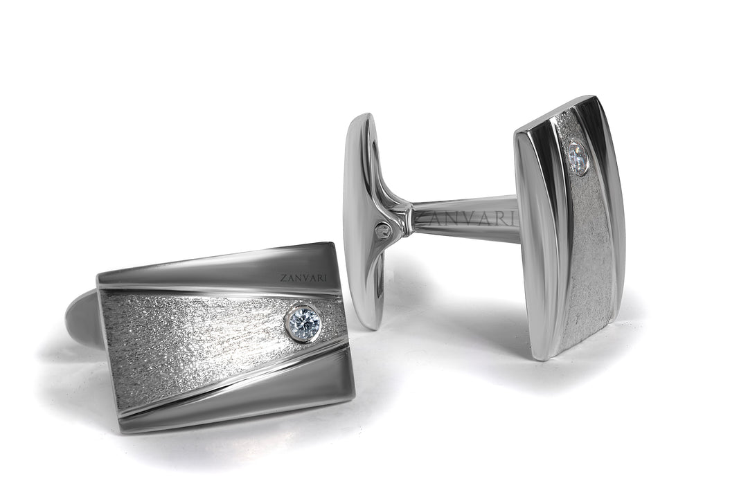Pair of silver cufflinks with a moissanite on a white background