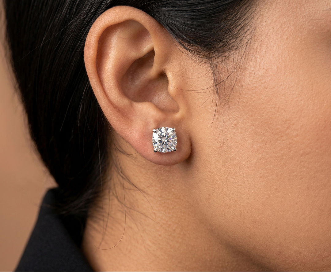 Close-up of an ear wearing a moissanite cushion cut earring with a blurred background