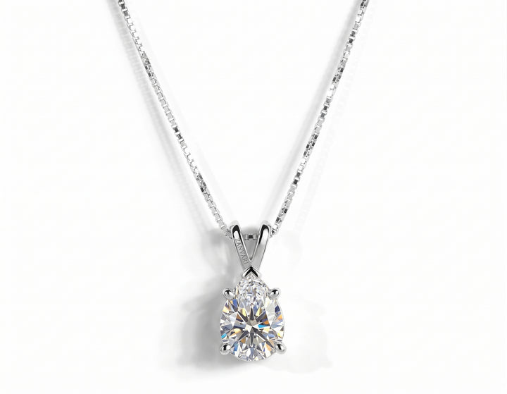 A pear-cut diamond pendant necklace in a silver four-prong setting on a silver box chain, isolated on a white background.