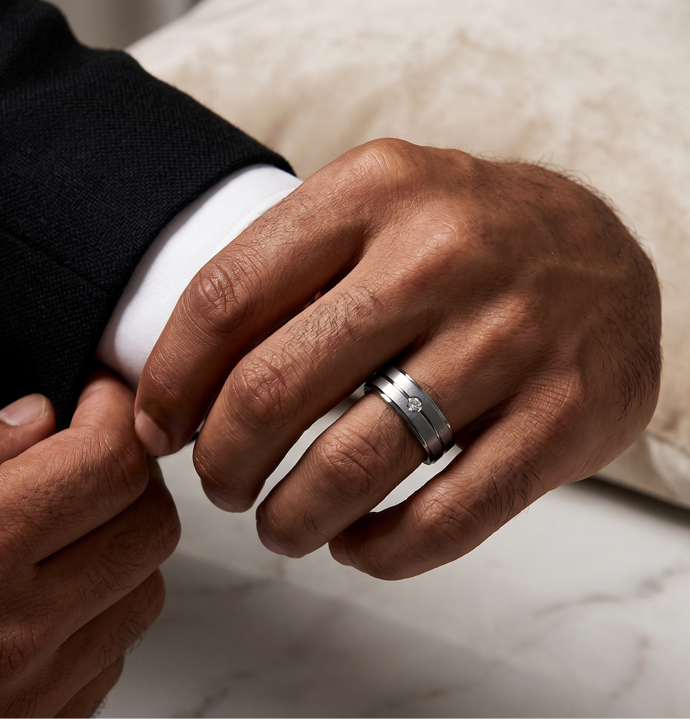 Close-up of a hand wearing a silver moissanite ring on a neutral background