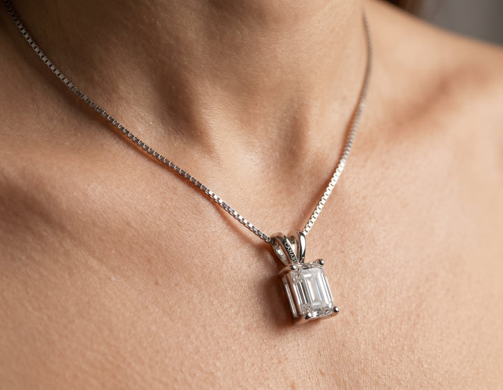 Model wearing the Eco Wonder Necklace, a 2ct emerald cut moissanite pendant hanging lengthwise on an 18-inch silver box chain
