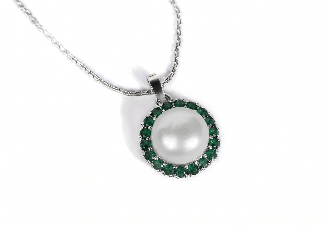 A silver pendant necklace featuring a large white pearl surrounded by a halo of small green emerald gemstones, shown on a clean white background.