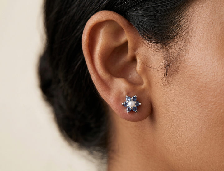 Close-up of an ear wearing a diamond earring with a neutral background