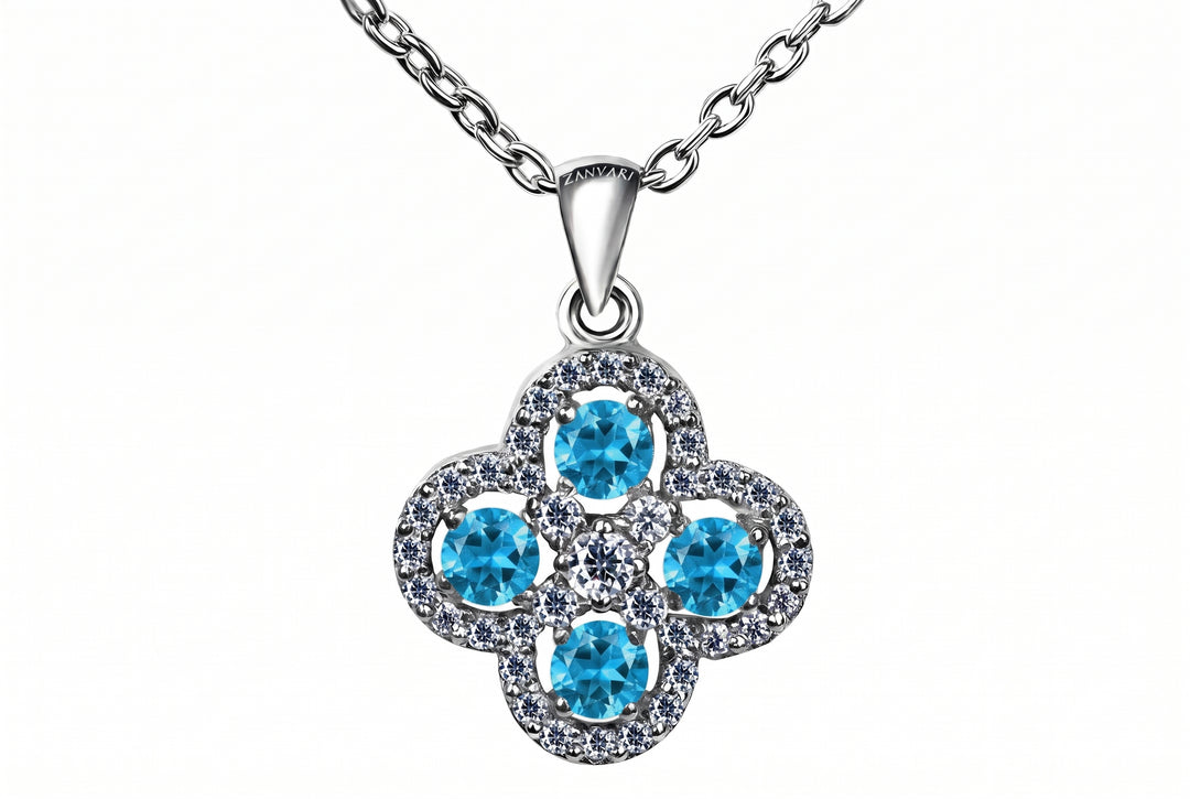 A silver-tone floral pendant necklace featuring four round light blue gemstones surrounded by small clear stones, suspended from a silver chain on a white background.