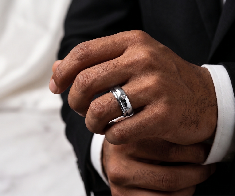 Close-up of a hand wearing a silver moissanite ring with a blurred background