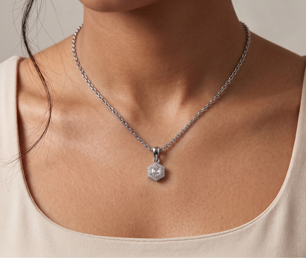 Necklace with a pendant hexagon cut moissanite worn by a person against a neutral background