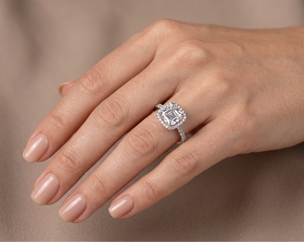 Hand wearing a moissanite proposal ring on a neutral background