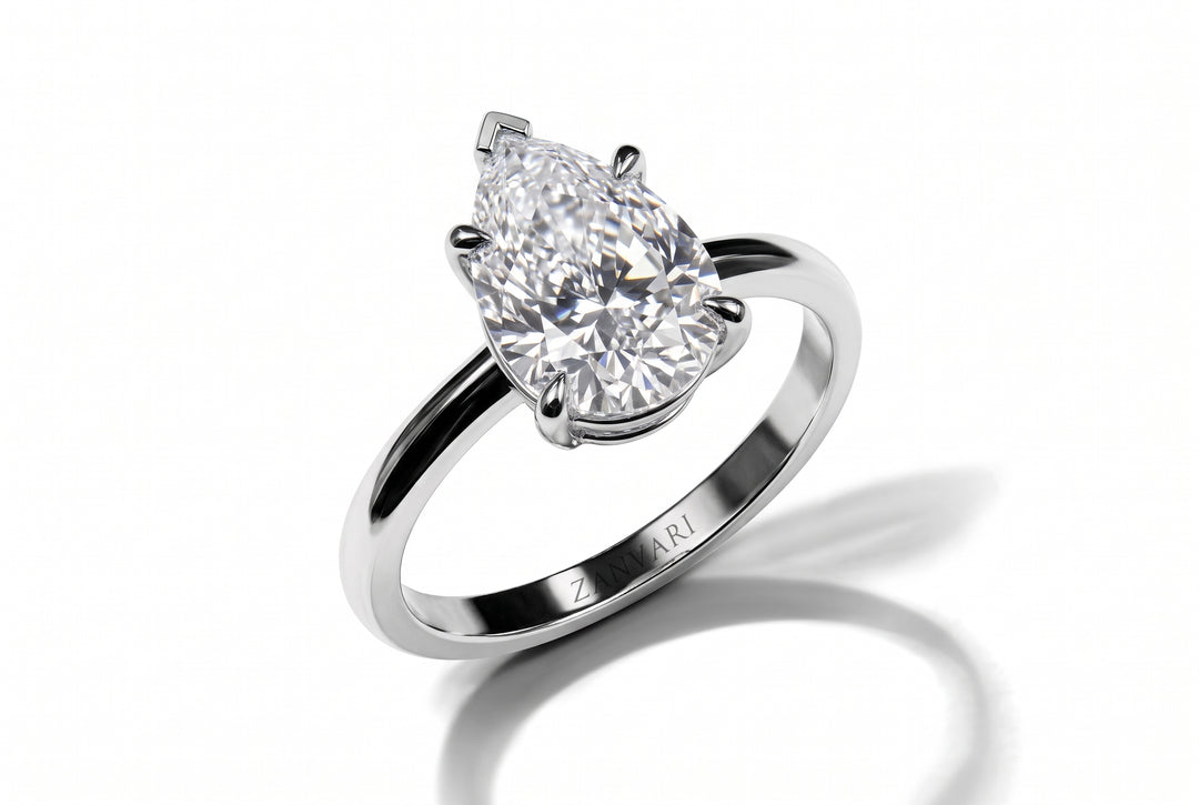 Classic pear-cut lab-grown diamond solitaire engagement ring set in a four-prong white gold band with an engraved Zanvari inner hallmark, displayed on a clean white reflective surface.