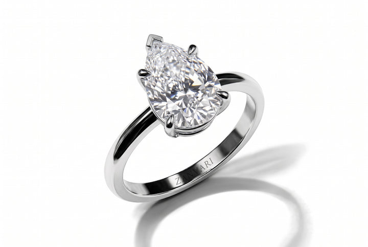 Classic pear-cut lab-grown diamond solitaire engagement ring set in a four-prong white gold band with an engraved Zanvari inner hallmark, displayed on a clean white reflective surface.