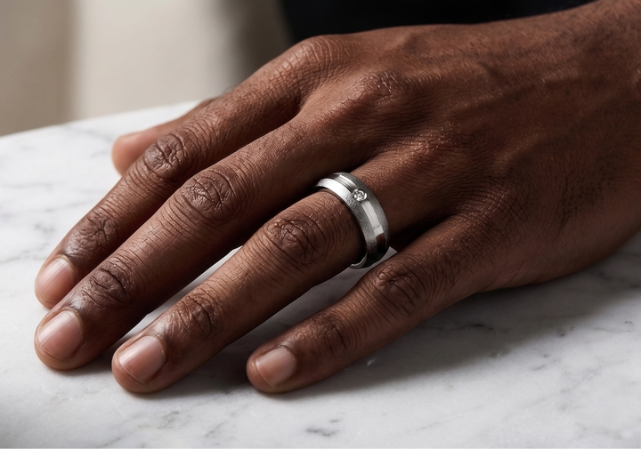 Hand wearing a silver ring on a marble surface